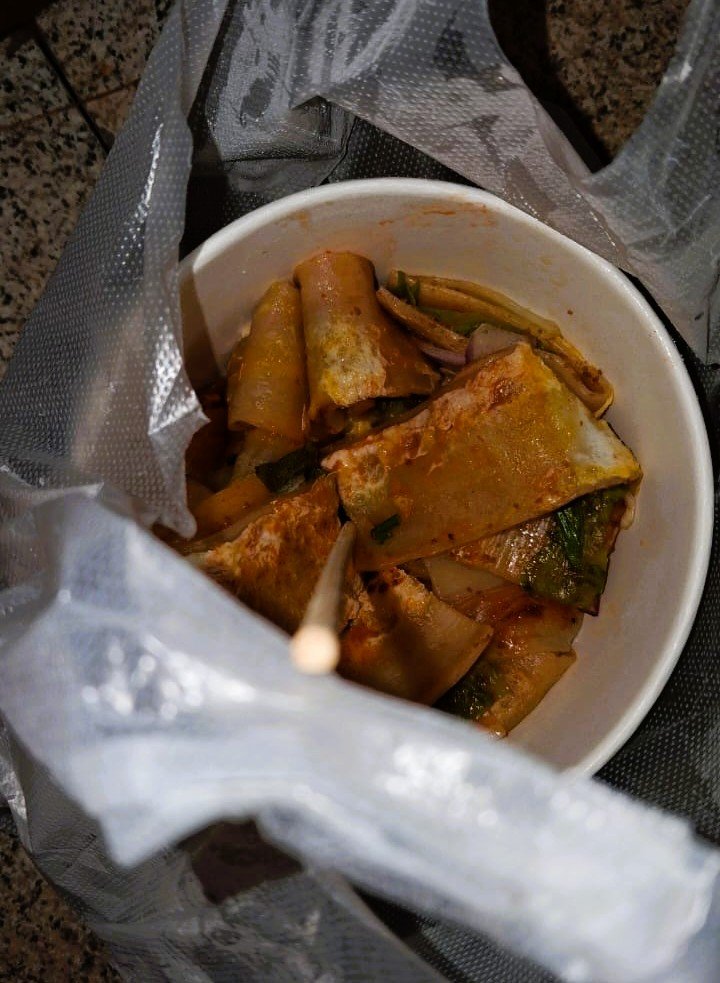 A bowl of kaolengmian grilled cold noodle sheets with vegetables and egg sauce from a night market in Hainan China