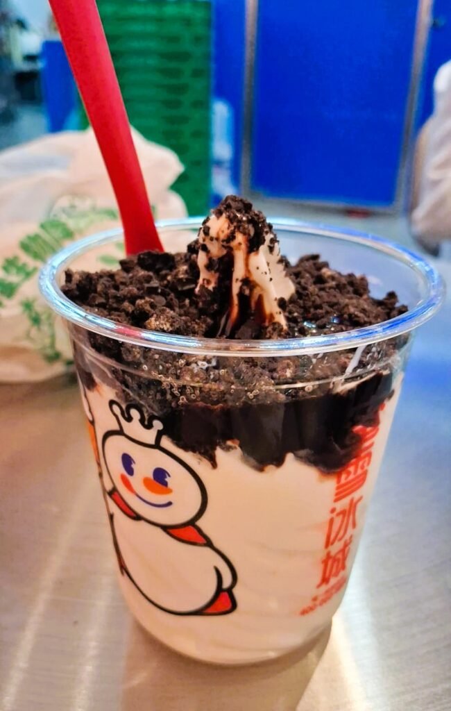 A Mixue branded cup filled with vanilla soft serve and crushed Oreo topping at a Mixue store in China