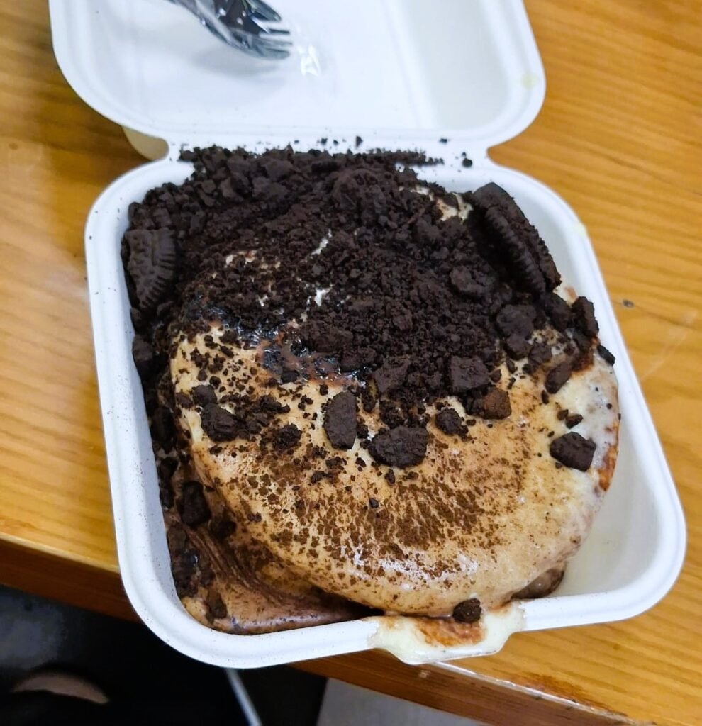 A fluffy Oreo soufflé with crushed cookie topping in a takeaway box from a night market in Hainan China